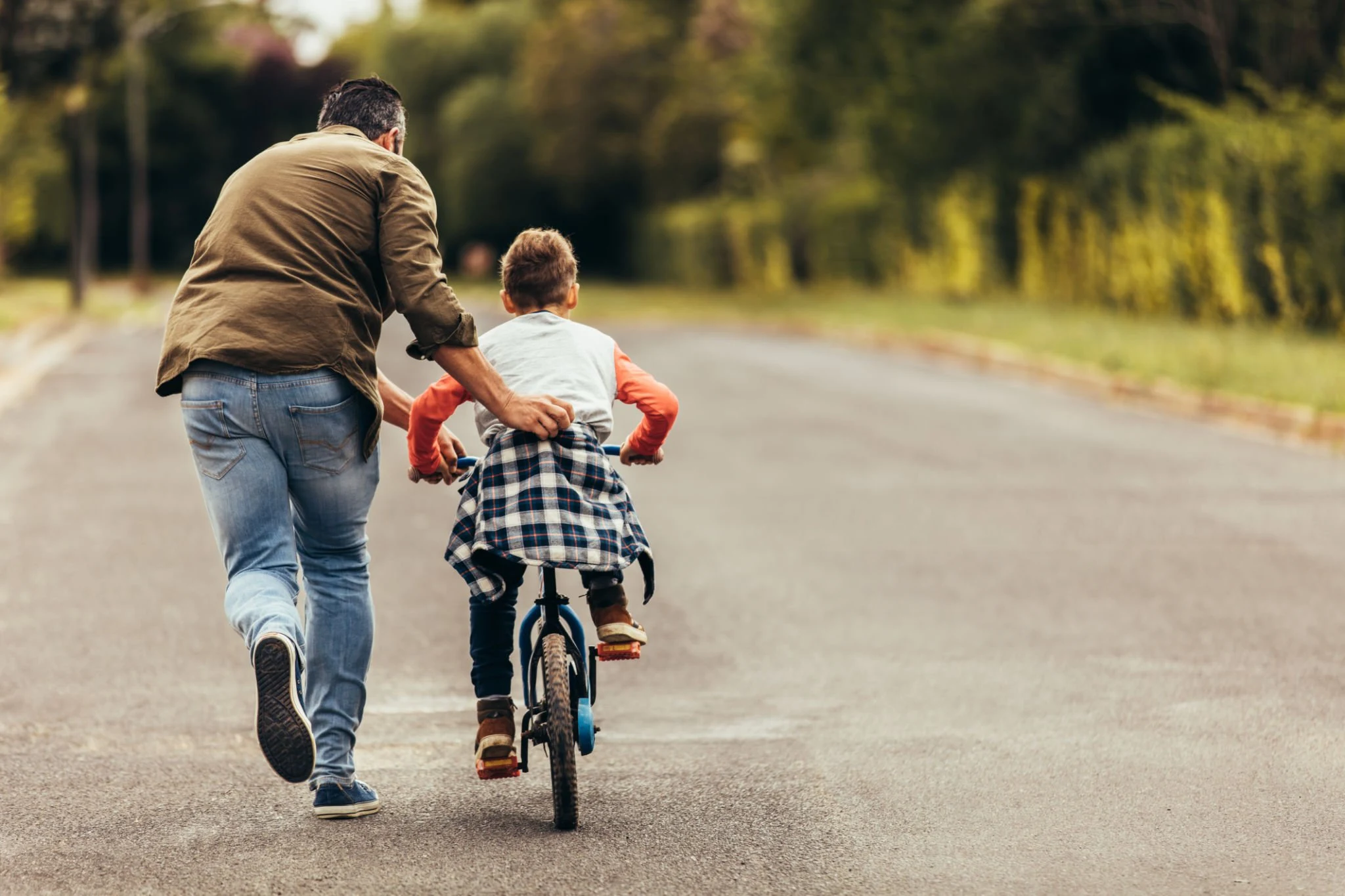 Man helping his kid in learning to ride